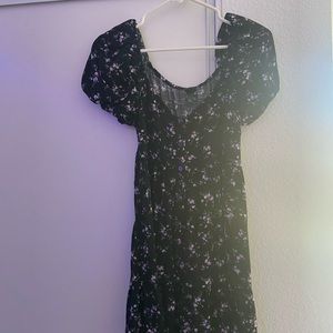 A black frilly dress with puffed sleeves and a purple flower pattern